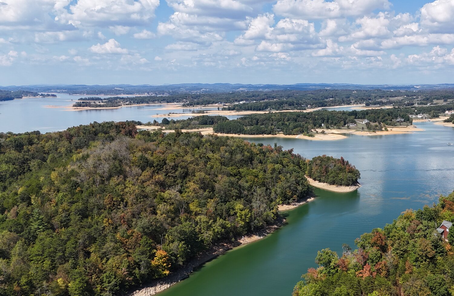 Aerial lake shoreline surrounded by wooded ridges